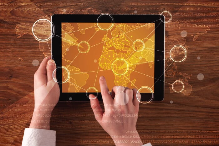 Header image for the "Home" page on the GOL-IT website containing two human hands holding a tablet with orange vector graphics map. The image over it has multiple circles and thin white lines graphics.